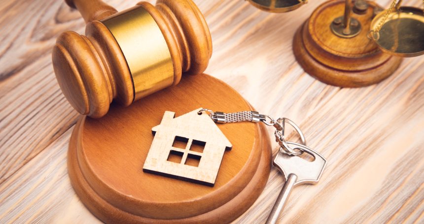 Judge gavel and house key on wooden background. Desalojo en ciudad vieja