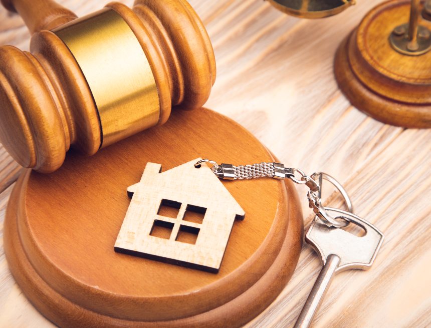 Judge gavel and house key on wooden background. Desalojo en ciudad vieja